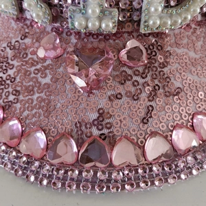 Detail of pink sequins, heart-shaped gems and pearl trim on a flat top party cap