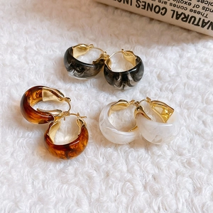 Detailed shot of resin U-shaped hoop earrings in amber, marble, and cream finishes