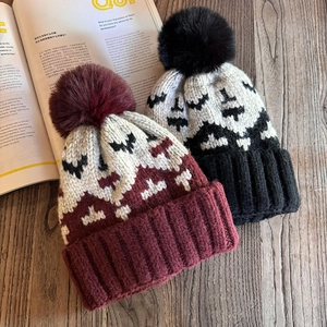 Nordic retro knit beanie with geometric pattern and fluffy pompom on wooden background