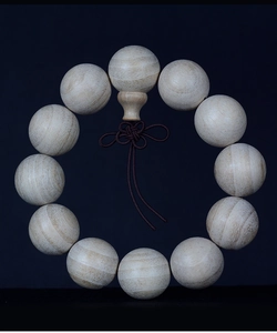 Detailed view of 12 natural camphor wood beads with visible texture and Chinese knot