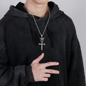 Detail of silver skull cross pendant on twist chain worn by model for retro style