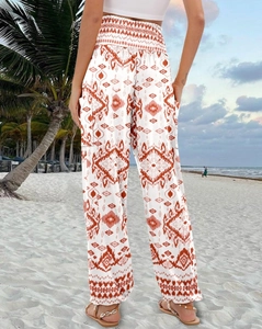 Detail view of high-waisted bohemian wide-leg pants with orange geometric print on beach