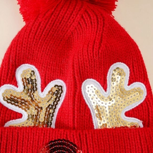 Detail of red Christmas knit hat with golden sequin antlers and thick texture