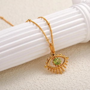 Detailed close-up of a golden eye-shaped pendant with a green gemstone on a marble pillar