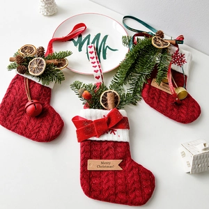 Tres calcetines navideños de punto rojo con borde de piel blanca y adornos de piñas naturales