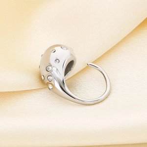 Macro shot of silver teardrop ring with sparkling crystals on champagne satin fabric