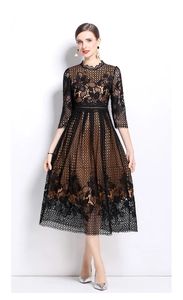 Détail d'une robe midi élégante en dentelle noire ajourée avec doublure beige et fleurs