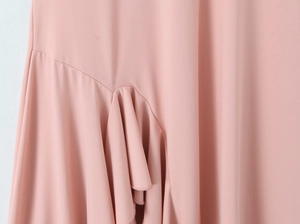 Vue détaillée du tissu rose à volants avec coutures délicates et texture lisse de la robe