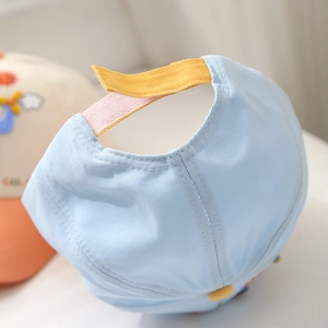 Detail of adjustable Velcro strap on a light blue cotton baseball cap for toddlers
