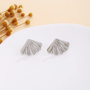 Macro view of silver shell-shaped earrings with radial ridges on a display stand