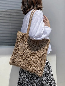 Handwoven straw shoulder bag with hollow floral patterns and brown leather straps for summer