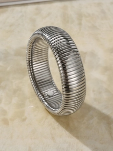 Macro detail of silver Tubogas style wide metal bracelet with industrial pleated texture