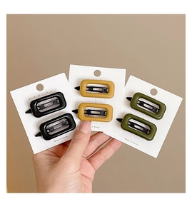 Close-up of three pairs of vintage resin rectangular hair clips in black, yellow, and green