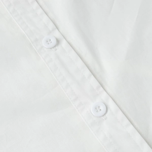 Detailed close-up of white buttons and smooth cotton fabric on long shirt dress