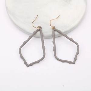 Detail of hollow geometric water drop earrings with grey matte finish on marble stand