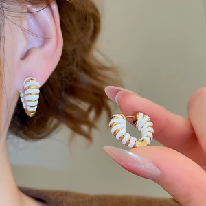 Détails de boucles d'oreilles spirales plaquées or 18 carats avec émail blanc sur le mannequin