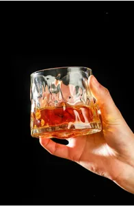 Macro shot of hand holding a textured whiskey glass with thick walls and amber liquid