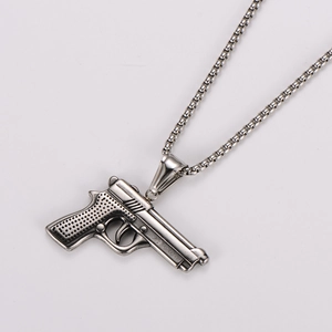 Detailed close-up of a silver pistol pendant with textured grip on a box chain necklace
