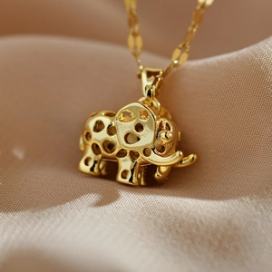 Detailed macro view of a hollow golden elephant pendant on a soft beige silk background