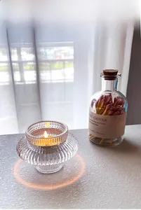 Détail d'un bougeoir en verre transparent à rayures avec une bougie chauffe-plat allumée