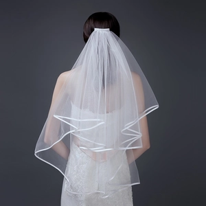 Detail of double-layer white bridal veil with ribbon edge and integrated hair comb