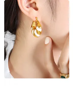 Close-up of a model wearing C-shaped gold and white enamel earrings with a vintage retro style