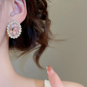 Detail of elegant gold stud earring featuring a pink oval crystal with diamond halo