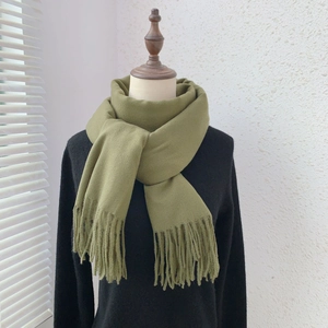 Detail of olive green knit scarf showing soft texture and long fringe tassels