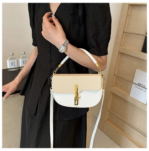 Chic color-block handbag with woven texture and gold chain worn by a model in black