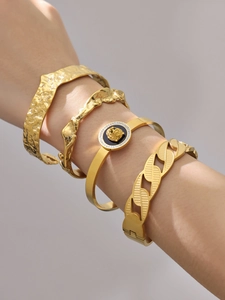 Close-up of hammered 18k gold plated stainless steel bangles with a lion head charm