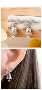 Detailed view of silver Christmas bell earrings with bow and star zircon accents