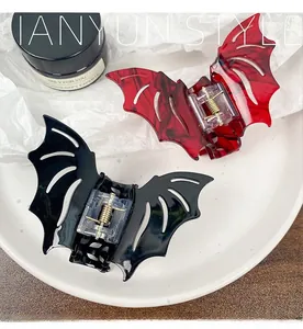 Detail of gothic bat wing hair claws in red marble and glossy black acetate