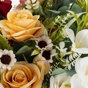 Detailed view of yellow and white artificial roses with small daisies and green foliage