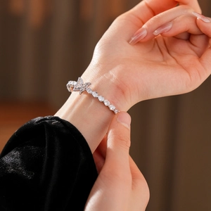Détail du bracelet papillon argenté avec pierres de zircone en forme de goutte au poignet