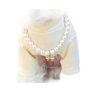Elegant pet pearl necklace with golden bow pendant and cat-eye stone on a small dog