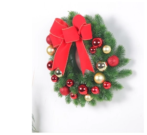 Close-up of a Christmas wreath featuring red bows, golden ornaments and pine needles