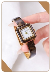 Detaillierte Makroansicht einer quadratischen Golduhr mit Schildpatt-Armband und Diamanten