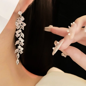 Close-up of long silver branch earrings with marquise-cut cubic zirconia worn by model