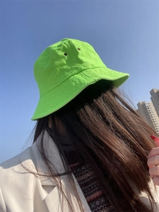 Detail of bright green cotton bucket hat with breathable eyelets against blue sky