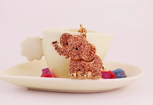 Macro shot of a pink rhinestone-encrusted elephant keychain pendant on a ceramic dish