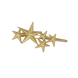 Detailed close-up of a gold metal hair clip featuring a row of five-pointed stars