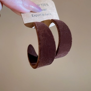 Détail de boucles d'oreilles en C floquées marron avec texture velours et étiquette Paris