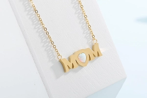 Macro view of gold MOM letter pendant with heart-shaped opal stone inlay on chain