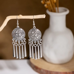 Detail view of vintage ethnic tassel earrings with antique silver metal texture on wood