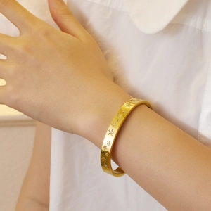 Detail of gold star engraved stainless steel bracelet with zircon inlay on wrist