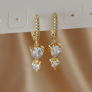 Detail of gold huggie earrings featuring sparkling round cubic zirconia and pavé stones