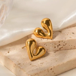 Polished 18K gold plated heart stud earrings on stone stand with silk background