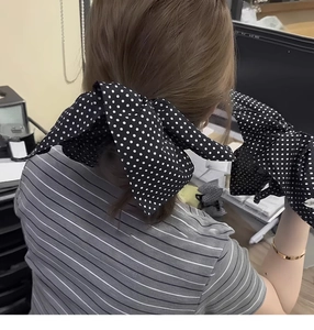 Close-up of retro black and white polka dot bow hair accessory and matching gloves