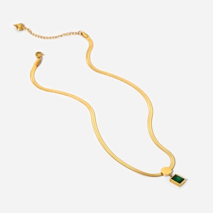 Flat lay of gold snake chain necklace with green square zircon pendant on white background