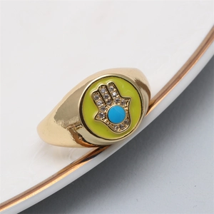 Detailed close-up of golden Hamsa Hand ring with yellow enamel and a blue center stone